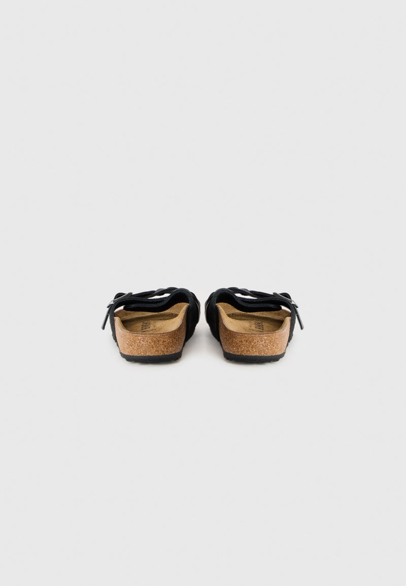 Schwarze Wildleder-Slipper mit Korkfußbett, strukturiertem Außensohl und schwarzen Riemen. Entworfen für Komfort und legere Freizeitmode.