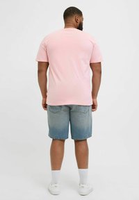 Hele roosa lühikeste varrukatega T-särk koos kulunud siniste denimšortidega. Šortidel on ragistatud äär ja kaks tagumist taskut. Valged sokid ja kingad.