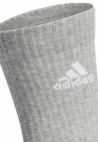 Calcetín de algodón gris con una textura suave, que presenta un logo blanco de Adidas impreso en el tobillo, estrechado en la parte superior para un ajuste ceñido.