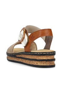 Sandale marron et beige avec une semelle en liège, dotée d'une large sangle avec une boucle circulaire marron et deux rayures blanches.