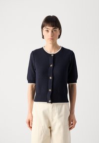 Navy knitted cardigan with short puff sleeves, ribbed cuffs and hem, featuring a round neckline and seven beige buttons down the front.