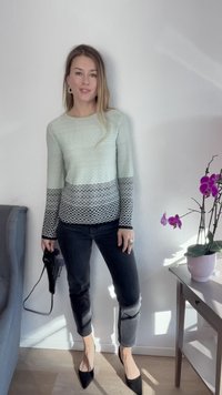 Suéter verde menta claro com padrão texturizado, design de treliça cinza na barra e mangas, combinado com jeans justos pretos e sapatos de salto agudo.