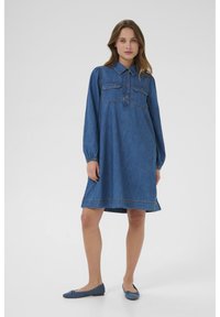 Zila džinsa krekla kleita ar garām piedurknēm, pogu aizdari priekšpusē, divām krūšu kabatām un brīvu, A-līnijas siluetu, ar šuvju detaļām.