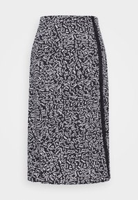 Jupe noire et blanche à motifs, longueur genoux, avec des formes abstraites, une texture lisse et une fente sur le côté.