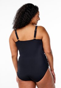 Maillot de bain noir une pièce avec des bretelles ajustables, un dos large et une texture lisse pour le confort. Conçu pour faciliter les mouvements.