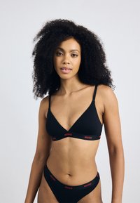 Zwarte katoenen triangle bralette en bijpassende bikini met rode "HUGO" logo band. Soepele textuur en minimalistisch ontwerp. Verstelbare bandjes.