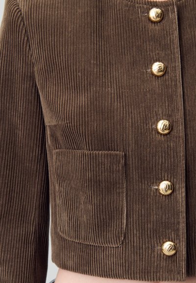 Giacca di velluto a coste marrone caratterizzata da righe verticali, un design corto, bottoni in tono dorato e una tasca frontale.