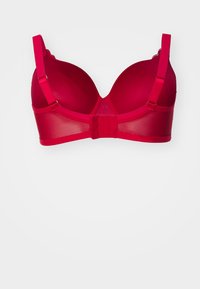 Röd bh med vadderade kupor, genomskinliga sidor och justerbara axelband. Har en spetskant längs kanterna och en hak-och-ögla bakstängning.