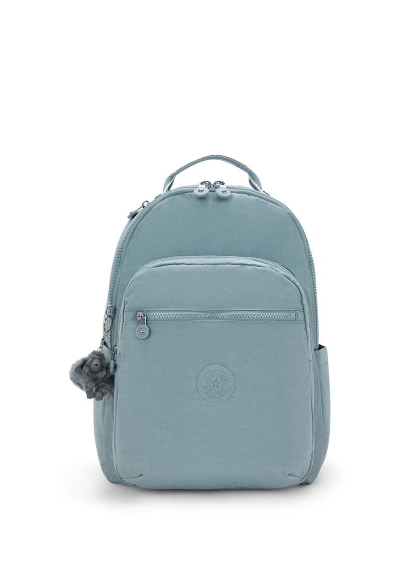 Mochila azul claro hecha de tela texturizada, con un bolsillo frontal con cremallera, un logotipo circular y un llavero decorativo de pom-pom de pelo.