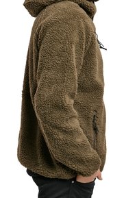 Giacca in pile marrone, morbida e pelosa, con cappuccio, dotata di tasca laterale con zip e superficie strutturata. Progettata per una vestibilità comoda.
