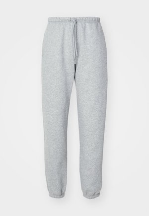 Pantaloni de trening gri, confecționați dintr-un material moale și texturat. Dispun de un talie elastică cu șnur, glezne conice și nu au modele sau logo-uri vizibile.