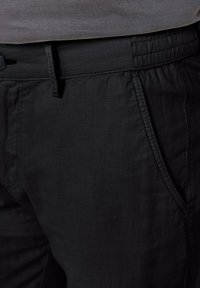 Black casual pants with a textured, lightweight fabric. Features a drawstring waistband, side pockets, and stitched detailing.