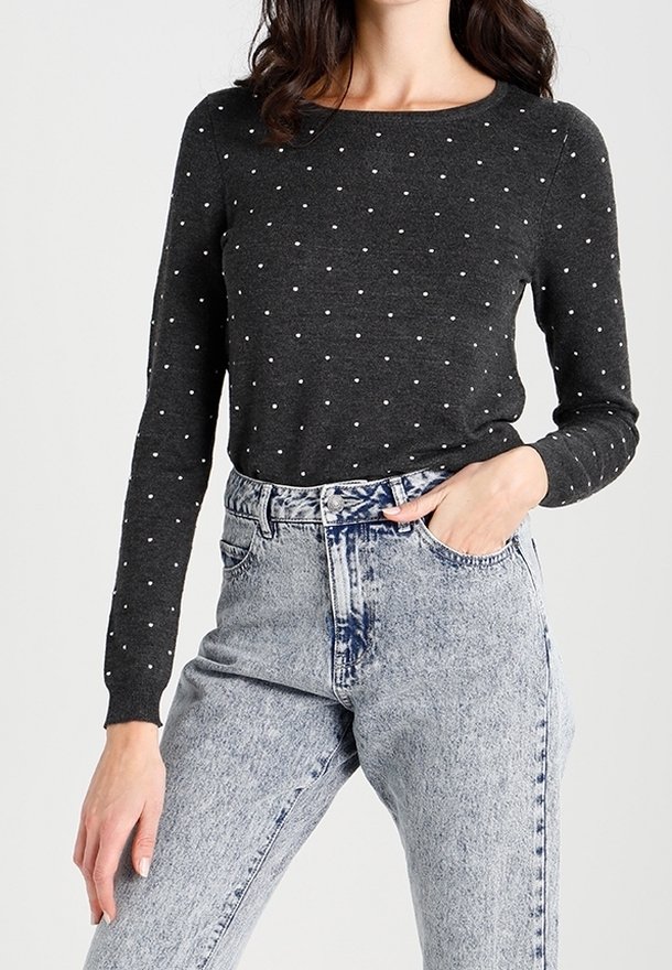 Szary sweter z długim rękawem w białe groszki, z okrągłym dekoltem, w połączeniu z jasnoniebieskimi, przetartymi jeansami z wysokim stanem.