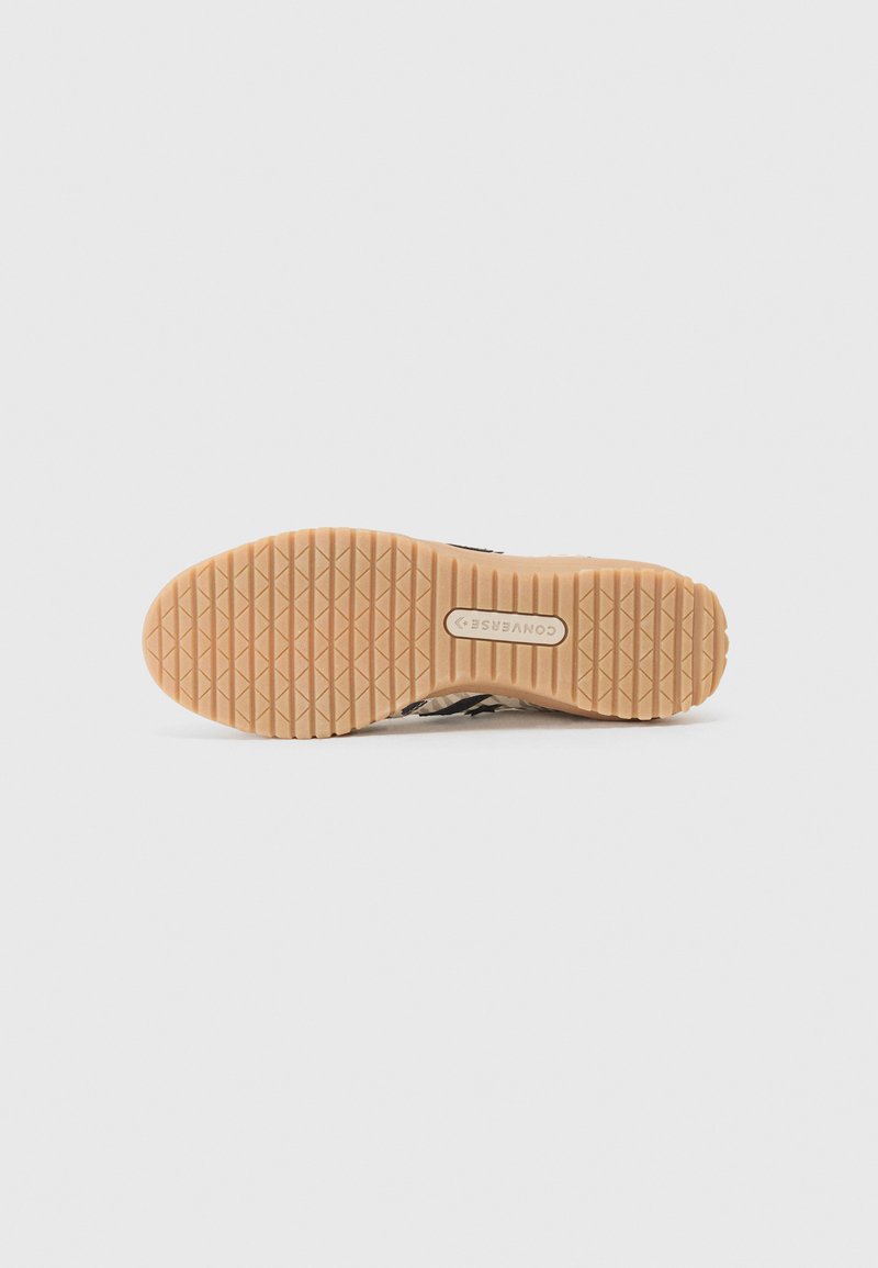 Suela de goma marrón con un patrón de agarre texturizado, parte de una zapatilla que presenta una parte superior de textil multicolor y detalles en negro.
