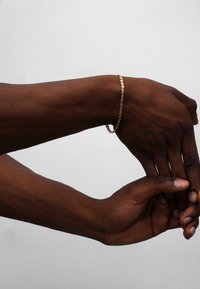 Gold chain bracelet on a wrist, featuring a linked design. The skin tone contrasts with the shiny metallic finish, highlighting the jewelry.