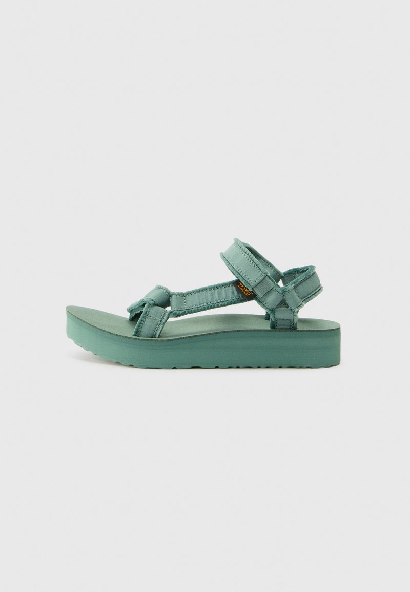 Teva sandals with a platform sole in a teal color. Features adjustable straps made of fabric and textured surface for grip.