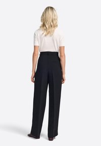 High-waisted black trousers with a wide-leg design, featuring pleats, a smooth texture, and a discreet back pocket detail.