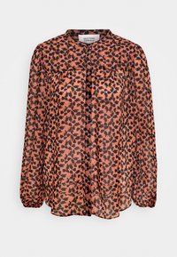 Genomskinlig blus med långa ärmar, rund halsringning och knäppning fram. Har ett mönster med rosa och svarta leopardfläckar.