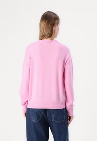Maglione in lana rosa con vestibilità morbida, orlo e polsini a coste, dotato di scollo rotondo e texture morbida. Vista dalla schiena.
