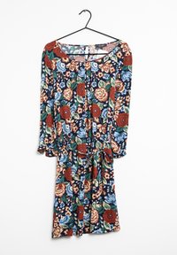 Blommig klänning med långa ärmar, marin bakgrund, med röda och blå blommor. Inkluderar midjeband och knappdetaljer på framsidan.
