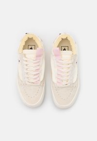Tenisky s krémově béžovým svrškem a růžovými akcenty. Mají texturované materiály, perforované detaily a šněrovací design.