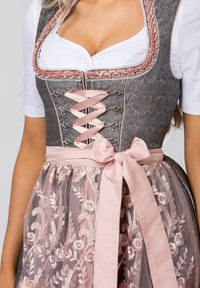 Traditional dirndl dress with a gray bodice, pink lace-up detail, and embroidered sheer pink skirt. Satin waistband tied into a bow.