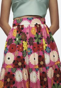 Bloemrokken met een roze basis met meerkleurige bloemen in diverse vormen. Gelaagd ontwerp en elastische tailleband. Licht, gestructureerde stof.