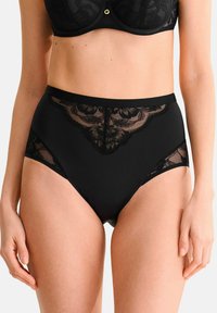 Culotte noire taille haute avec un panneau en dentelle transparente à l'avant et sur les côtés, dotée d'une ceinture en tissu lisse et de motifs en dentelle florale.