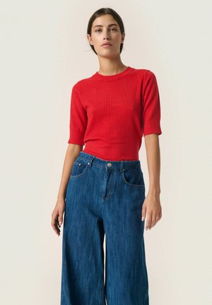 Red ribbed short-sleeve top paired with wide-leg blue denim pants. The top has a fitted design, and the pants feature a button closure and pockets.