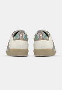 Weiße Sneaker mit einer strukturierten Ferse in Grau und Grün, orangefarbigen Akzenten und einer beige-gummierten Sohle mit Nahtdetail.