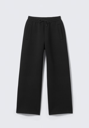 Pantalones deportivos negros de pierna ancha, con cintura ajustable mediante cordón y dos bolsillos laterales. Confeccionados en un tejido suave y texturizado.