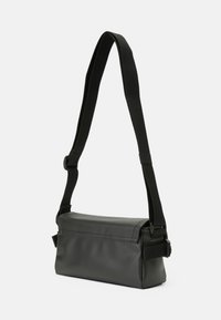 Juodas, stačiakampis crossbody krepšys, pagamintas iš lygios sintetinės medžiagos. Turi reguliuojamą petnešą ir minimalistinį dizainą be matomų elementų.