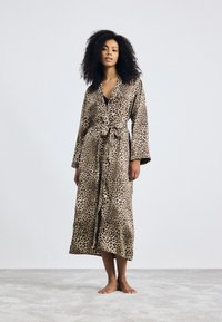 Robe en satin à imprimé léopard avec des manches longues, une ceinture à nouer et un design fluide. Texture douce et ourlet mi-mollet.