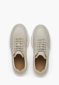 Beige tenisky se hladkým svrškem z kůže a semiše, perforovanou špičkou a textilními šňůrkami. Mají bílou gumovou podrážku a detail značky uvnitř.