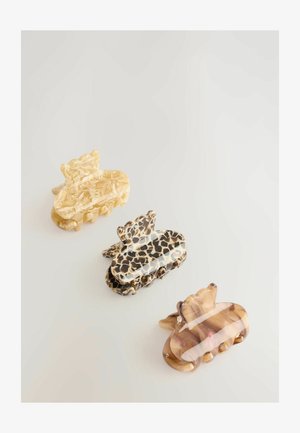 Fermagli in plastica di tre colori: crema con marmorizzazione, nero con motivo leopardato e marrone traslucido con striature, caratterizzati da un design curvo.