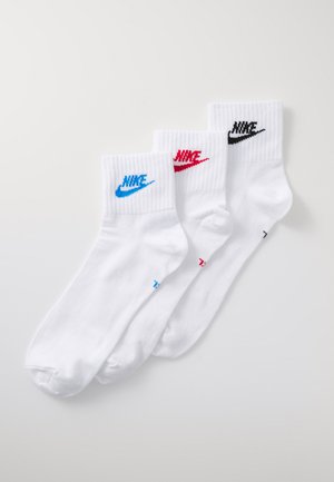 Calcetines de tobillo Nike blancos, con logotipos bordados en azul, rojo y negro en los puños estriados. Tejido suave con una forma estándar de calcetín.