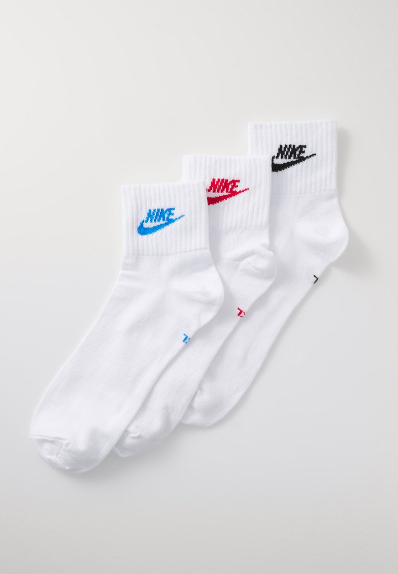 Fehér Nike bokazoknik, melyek kék, piros és fekete hímzett logókkal rendelkeznek a bordás szegélyeken. Puha anyagból készült, standard zokni formával.