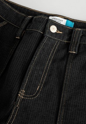 Jeans dritti neri a vita alta in tessuto testurizzato, con cuciture arancioni a contrasto e chiusura con bottone metallico visibile. Etichetta di cura inclusa.