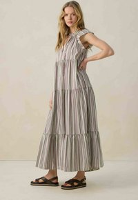 Robe maxi rayée avec volants superposés, dotée d'un décolleté en forme de trou de clé et de manches courtes. Le tissu est léger avec des rayures vertes, rouges et blanches.