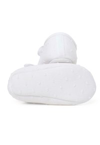 Pantof de țesătură albă cu un design texturat și punctat și o talpă moale. Prezintă un spate joasă și o mică etichetă pentru a fi ușor de încălțat și de dat jos.