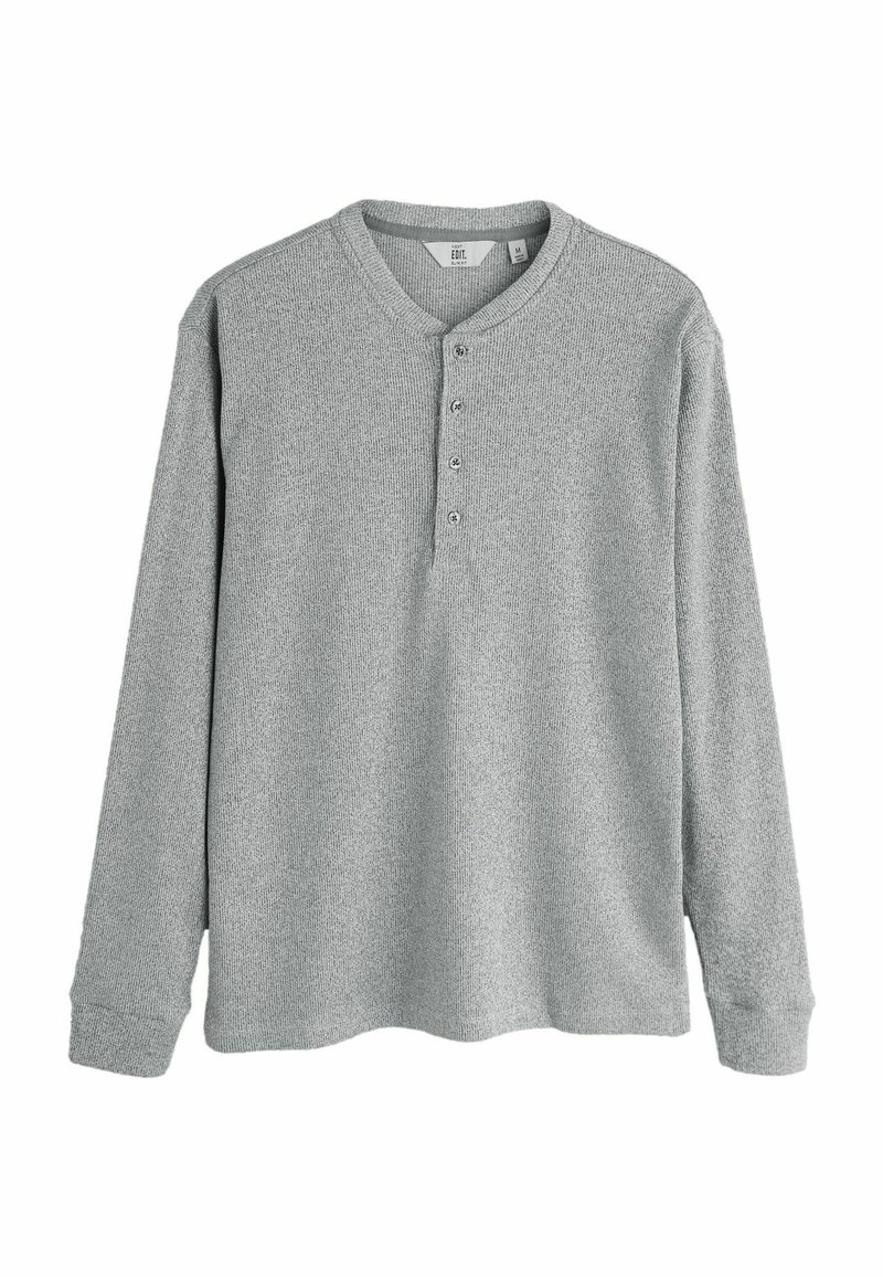 Lys grå langærmet henley skjorte med ribbet tekstur, rund krave og fire knapper foran. Blødt stof med en afslappet pasform.