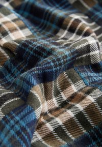 Multifarvet ternet stof med blå, brune og grønne nuancer og en blød tekstur. Mønsteret inkluderer varierende striber og tern.