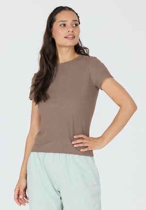 Bruin geribd T-shirt met korte mouwen en een ronde halslijn, gecombineerd met lichtmintkleurige broeken met een subtiele merketiket. Fijne textuur.