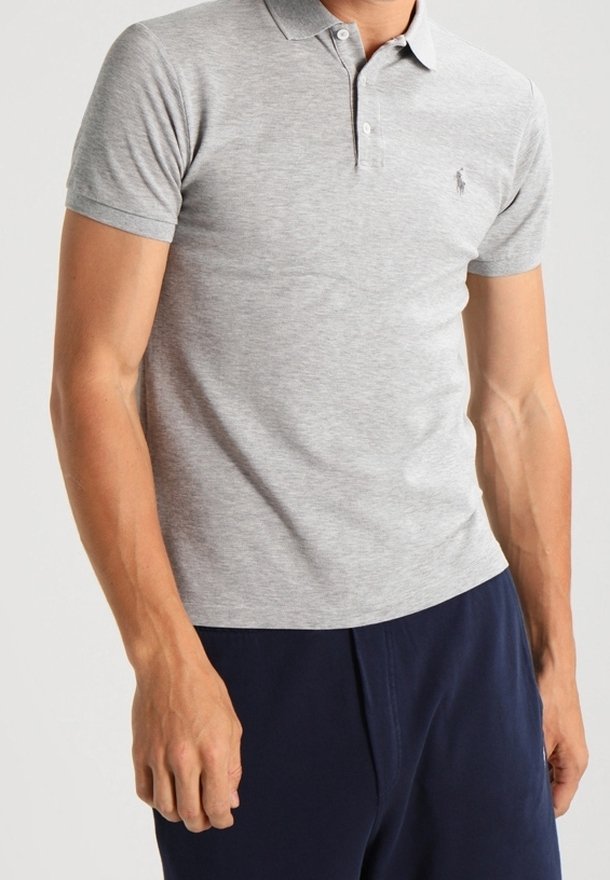 Man wearing a light gray short-sleeve polo shirt with buttons and navy blue pants, standing against a plain background.