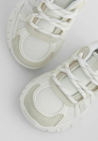 Baskets blanches en mélange de matières mesh et cuir, avec une surface texturée, un bout arrondi et des lacets plats. Accentué de détails beige clair.