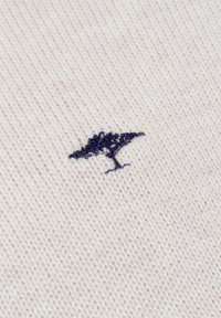 Witte gebreide stof met een klein, geborduurd blauw boomontwerp. De textuur is glad met een fijne, gelijkmatige weving.