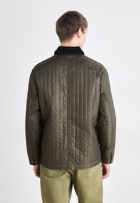 Gestepptes olivgrünes Jacket mit schwarzem Kragen, langen Ärmeln und geradem Schnitt. Verfügt über dezente Knöpfe und vertikale Nahtdetails.