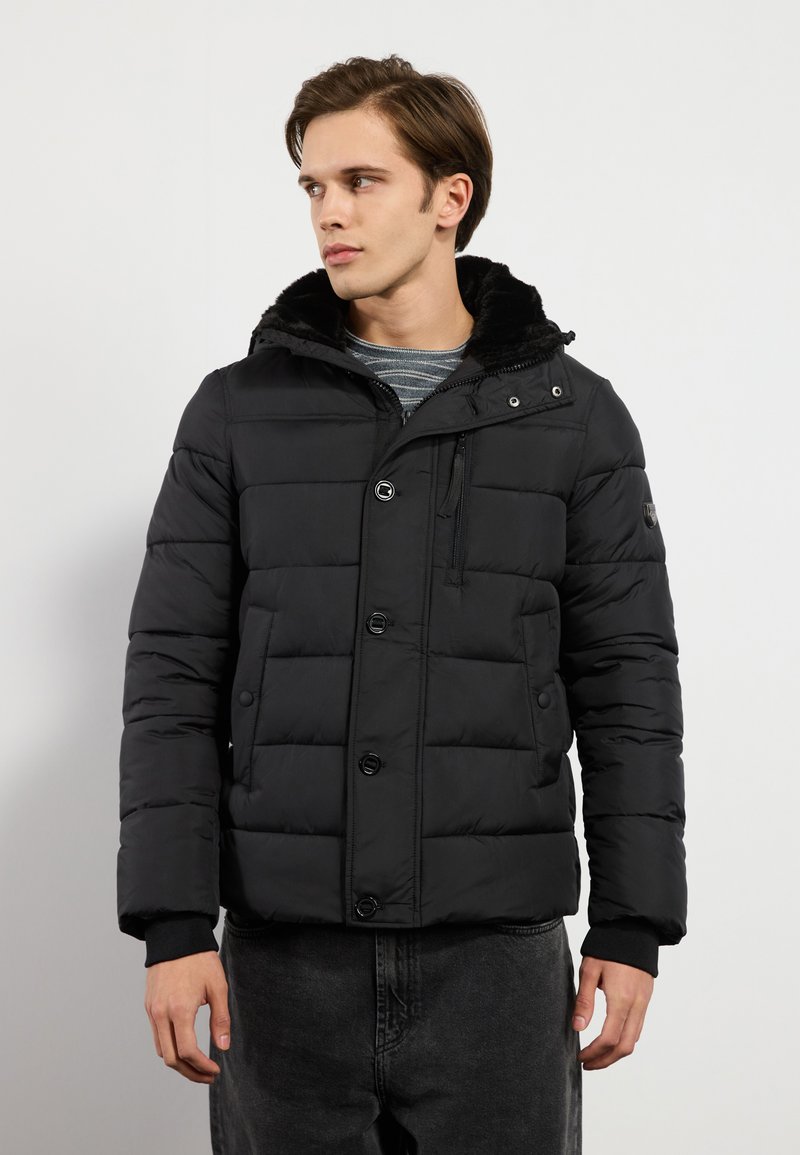 Chaqueta acolchada negra con cierre de botones en la parte delantera, capucha forrada de piel y puños acanalados. Presenta un diseño acolchado y bolsillos laterales.