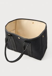 Μαύρη ορθογώνια τσάντα tote με μπεζ εσωτερικό, δύο μαύρες λαβές με λευκές ραφές και κουμπώματα με κούμπωμα κατά μήκος της άνω άκρης.