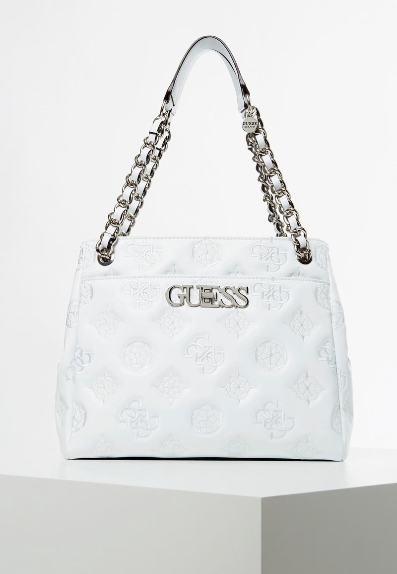 Sac à main matelassé blanc avec logos en relief, nom de marque "GUESS" argenté sur le devant, et anses en chaîne argentées avec accents de bandoulière en cuir.